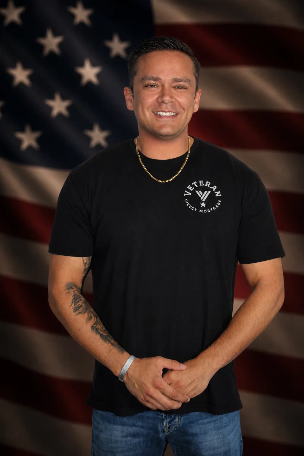 Javier Marino, co-founder of Veterans Direct Mortgages, wearing a branded shirt in front of an American flag
