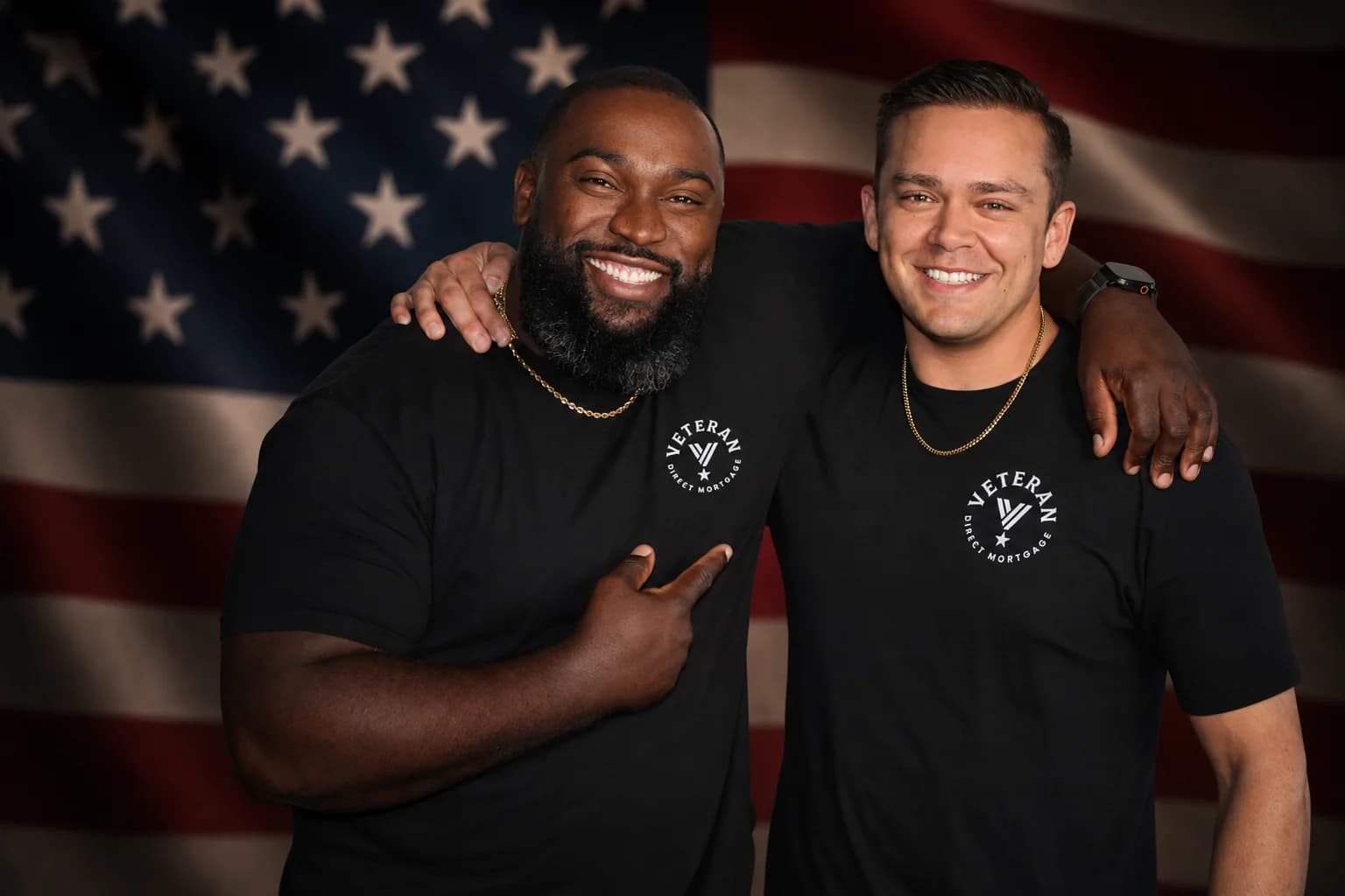 Co-founders Renaldo Wilson and Javier Marino of Veterans Direct Mortgages, in branded shirts in front of an American flag